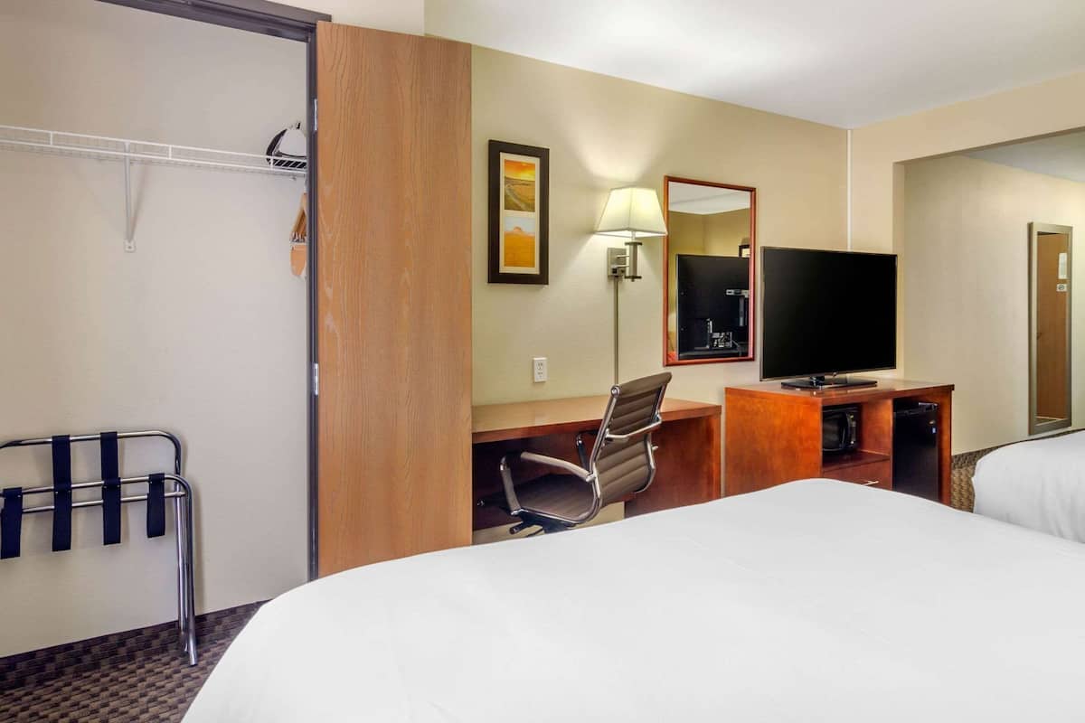 A hotel room with a bed, desk, chair, TV, and a mirror.