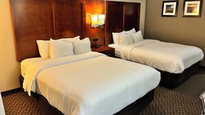 A hotel room with two beds, a wooden headboard, a nightstand, a lamp, and two framed pictures on the wall. - Comfort Inn & Suites Sterling (Sterling)