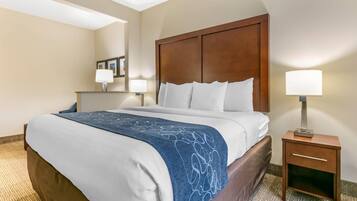 A hotel room with a bed, bedside table, lamp, and a mirror on the wall.