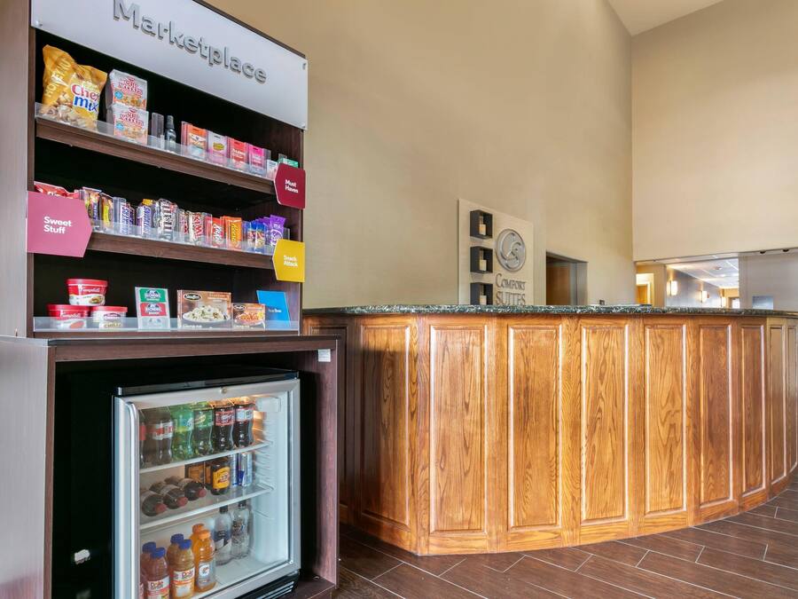 Una kitchenette con un refrigerador lleno de bebidas, un microondas y una cafetera.