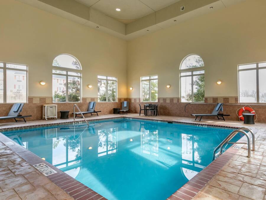 A pool area with clear blue water, sun loungers, and a lifebuoy.