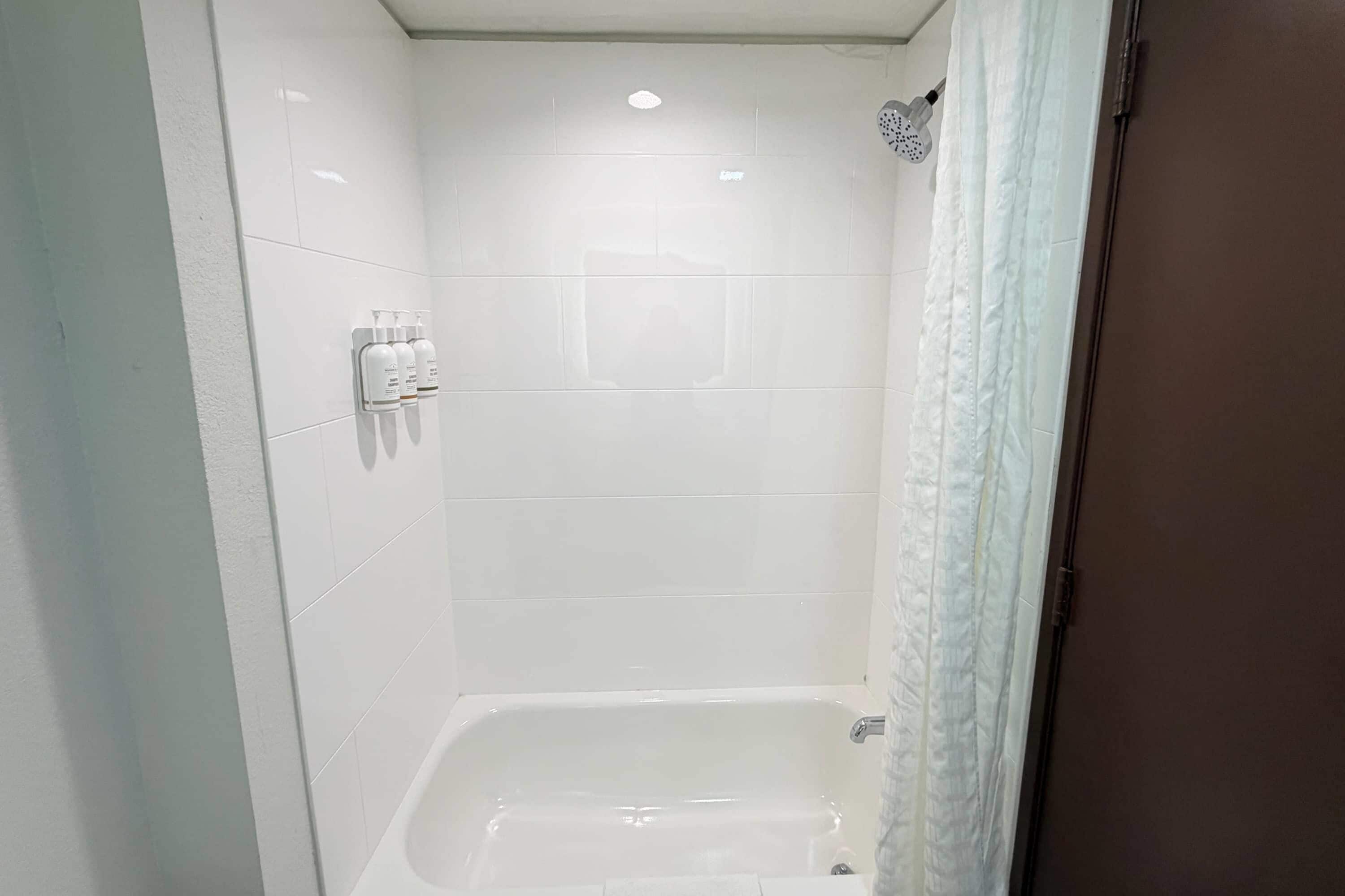 Une salle de bain avec des carreaux blancs, une douche et des toilettes.