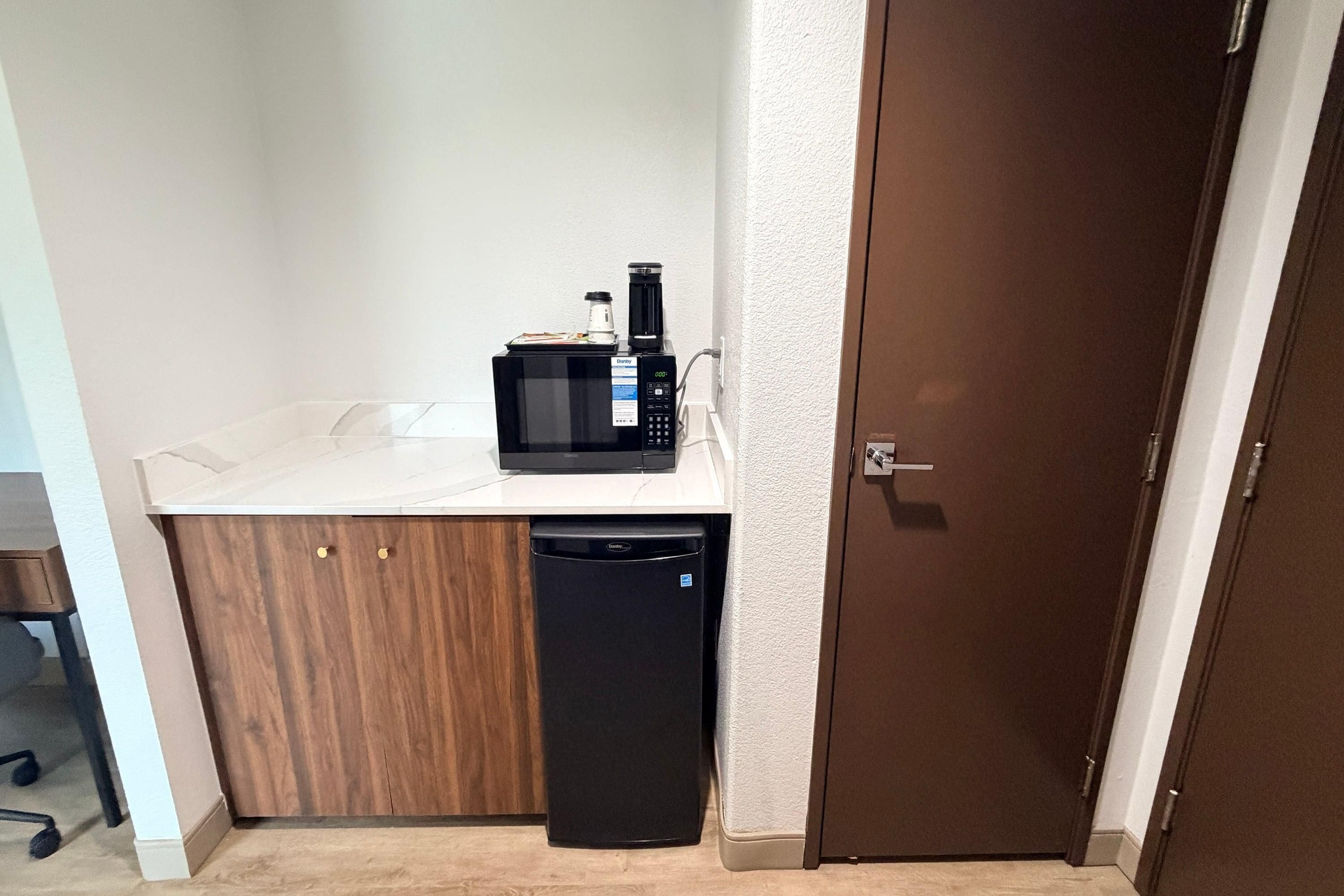 Una kitchenette pequeña equipada con microondas, cafetera y lavavajillas.