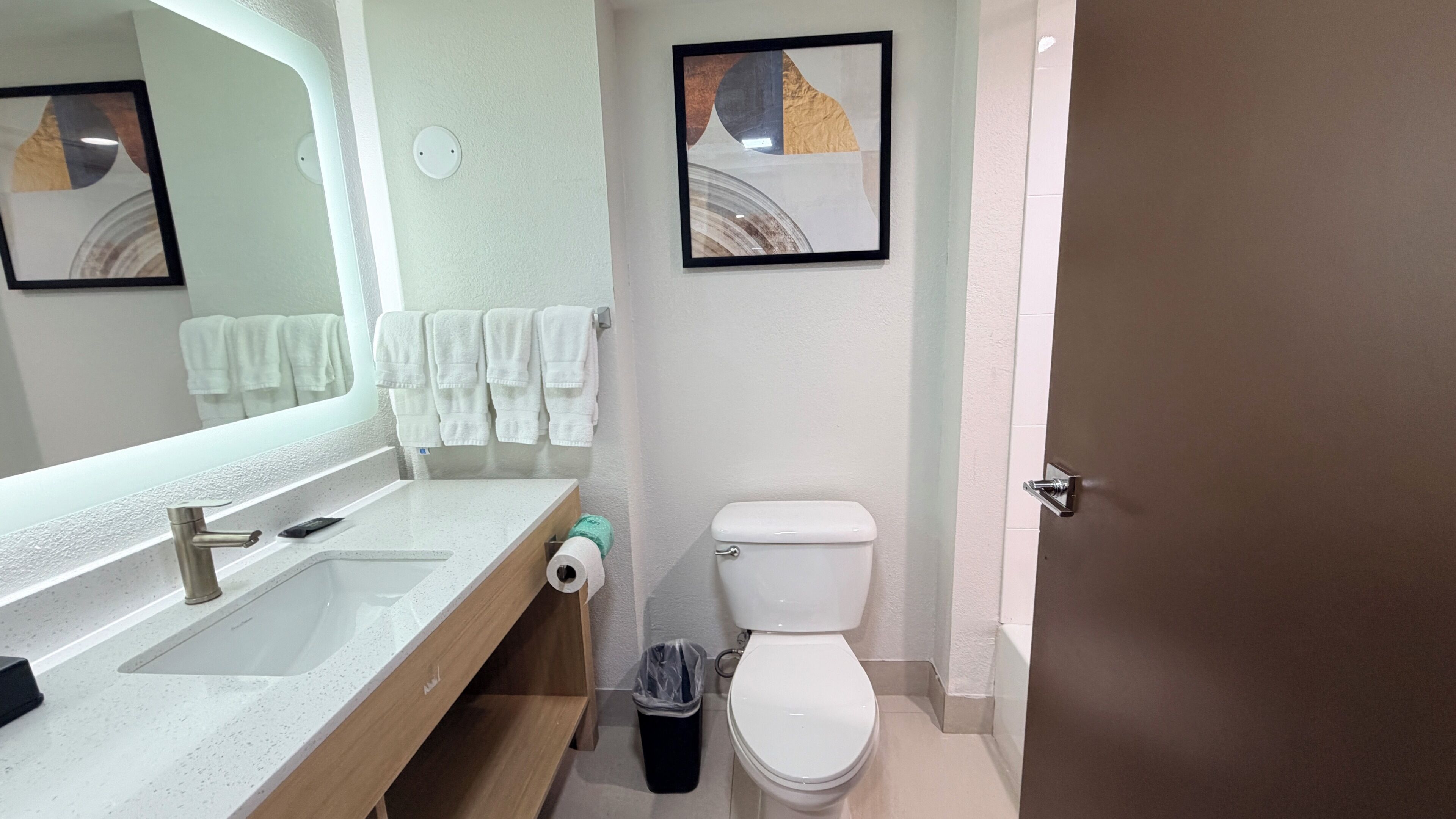 A bathroom with a sink, mirror, toilet, and towel rack.