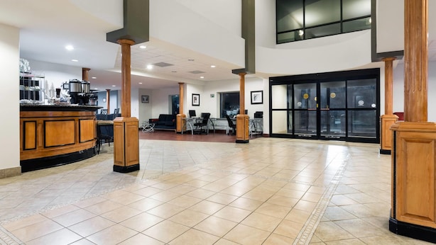 A spacious lobby with a reception desk, seating area, and a large glass door entrance.