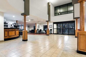 A spacious lobby with a reception desk, seating area, and a large glass door entrance.