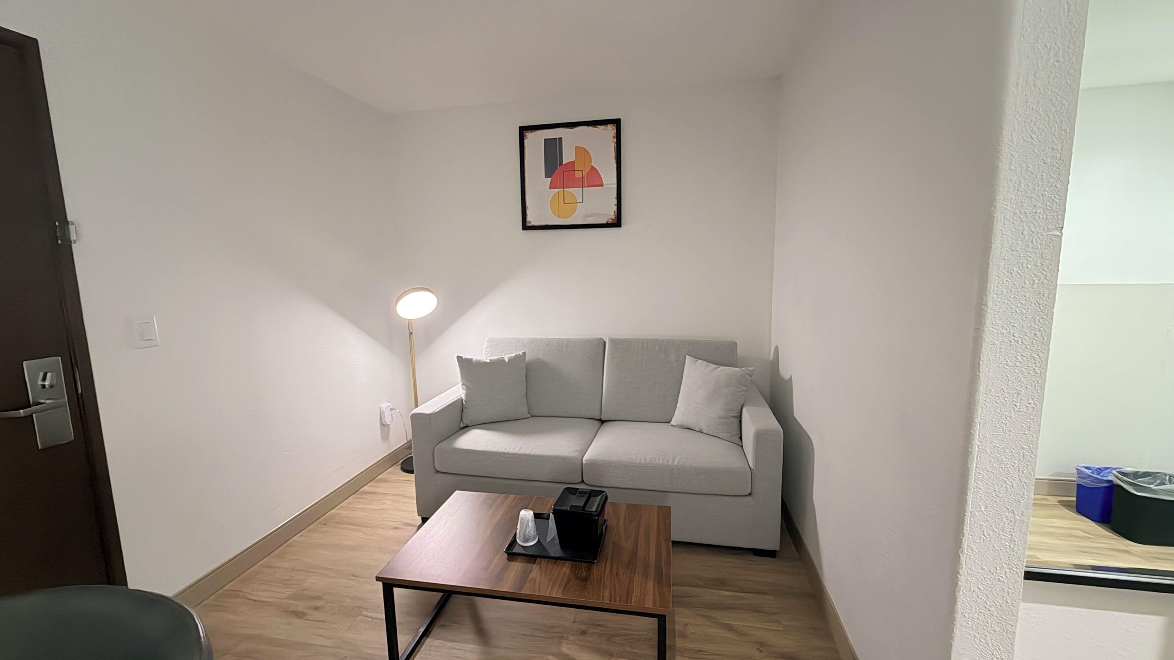 Een knusse, moderne woonkamer met een bank, een salontafel en een vloerlamp.