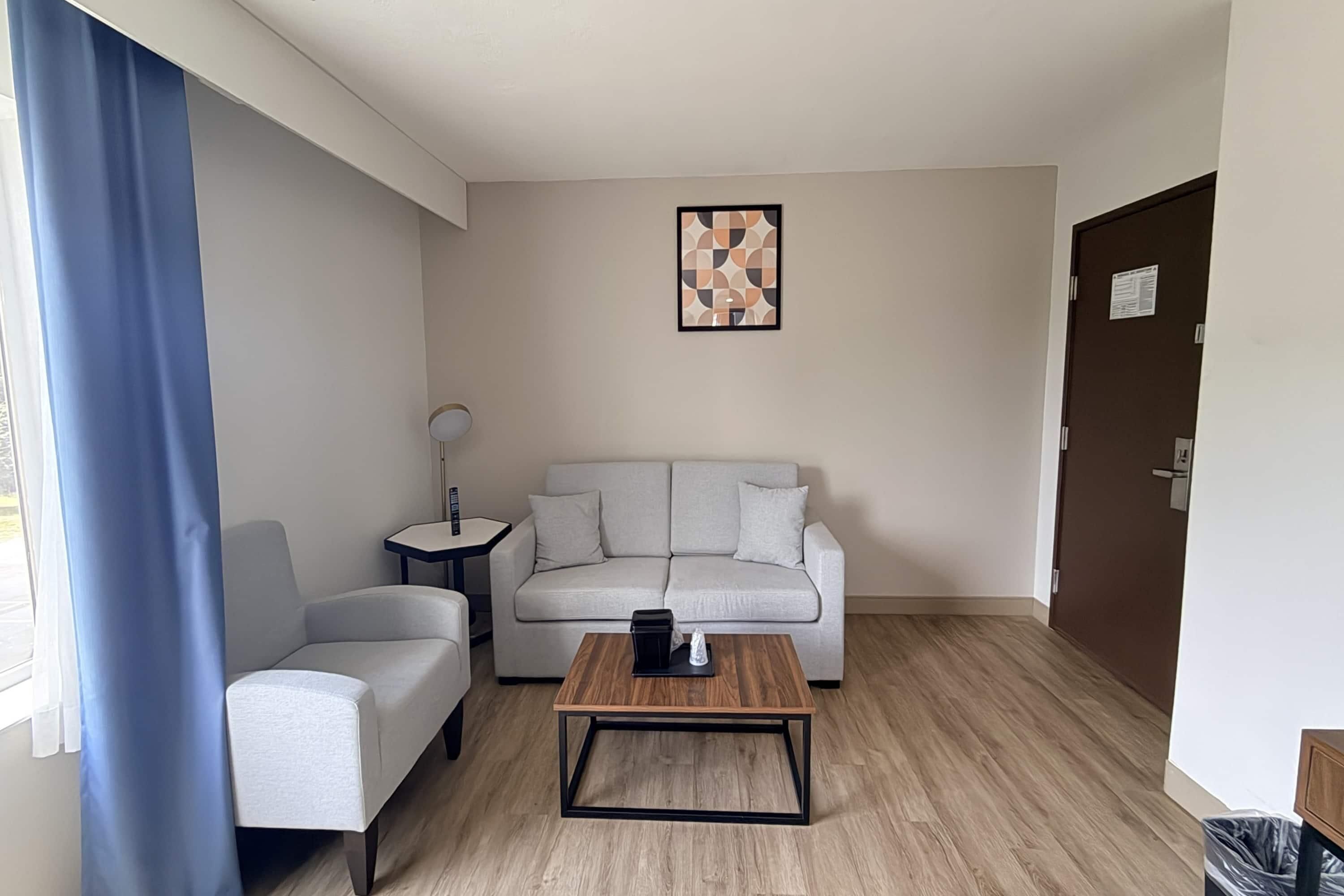 A modern living room with a sofa, a coffee table, a side table, and a wall art piece.