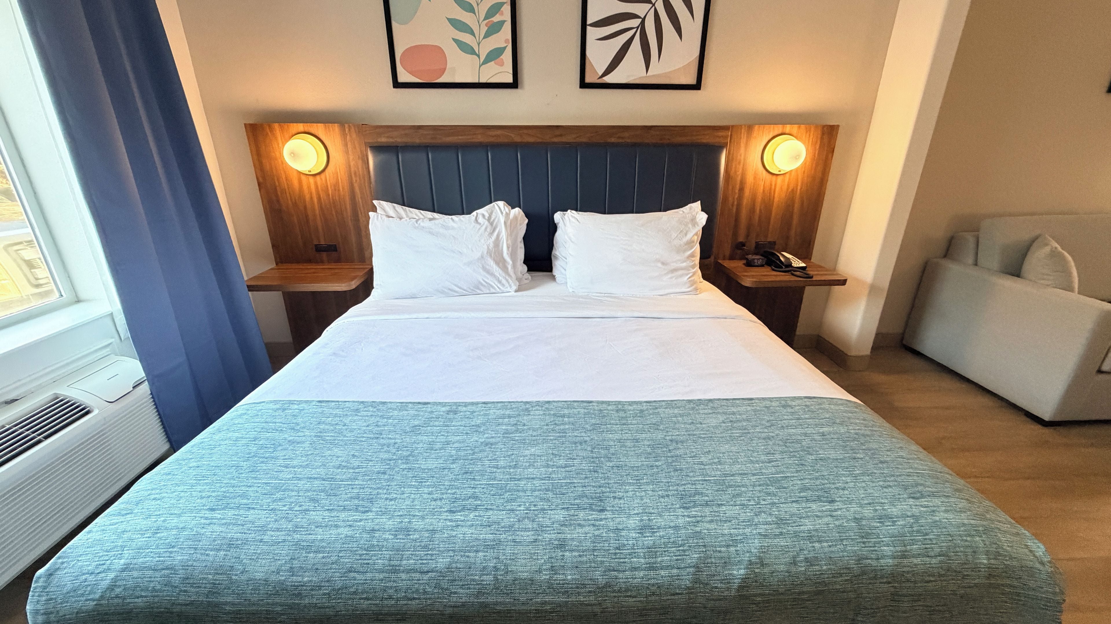 Ein Hotelzimmer mit Bett, Nachttischen, Schreibtisch und Stuhl.