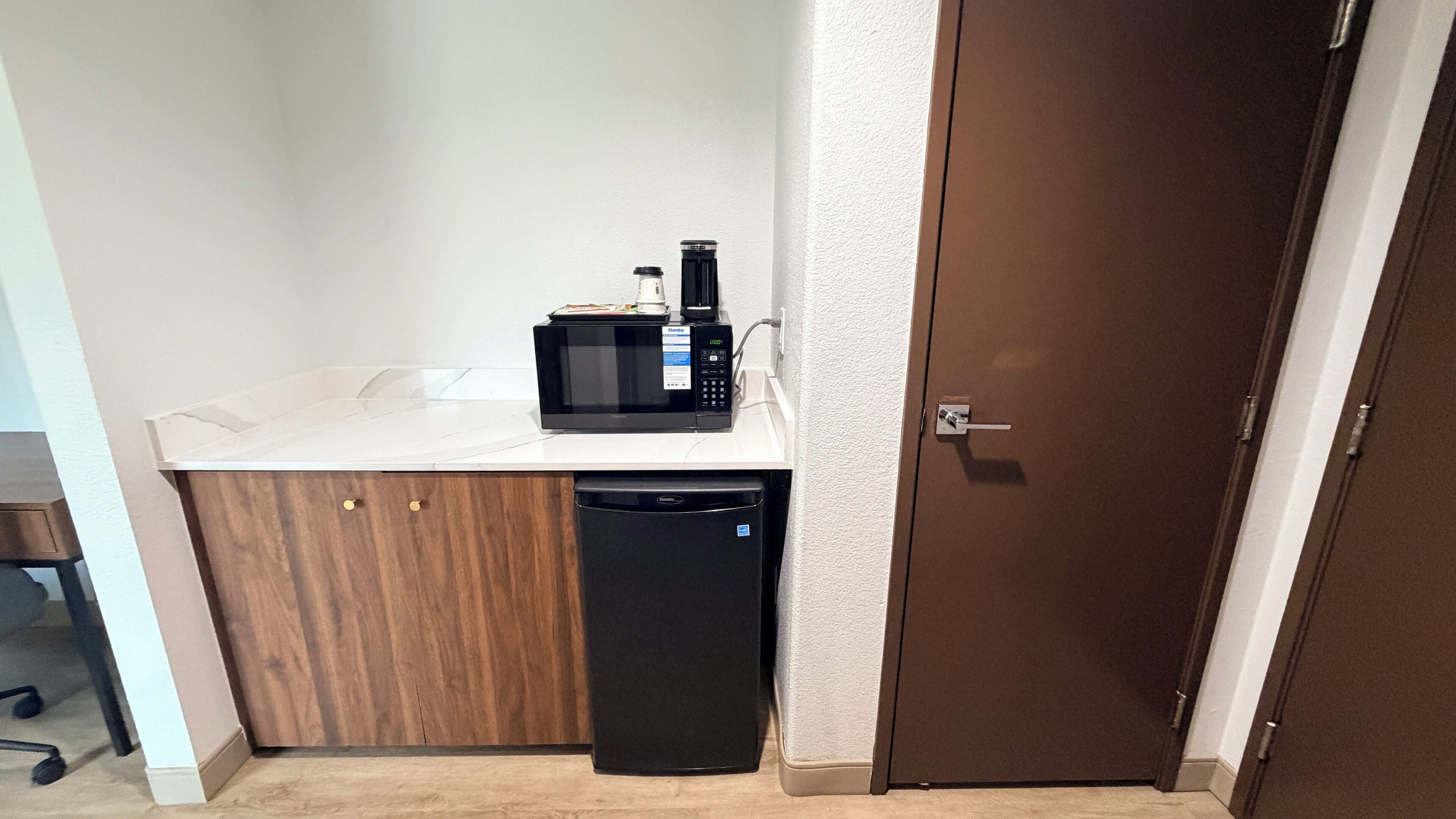 A kitchenette with a microwave, coffee maker, and dishwasher.