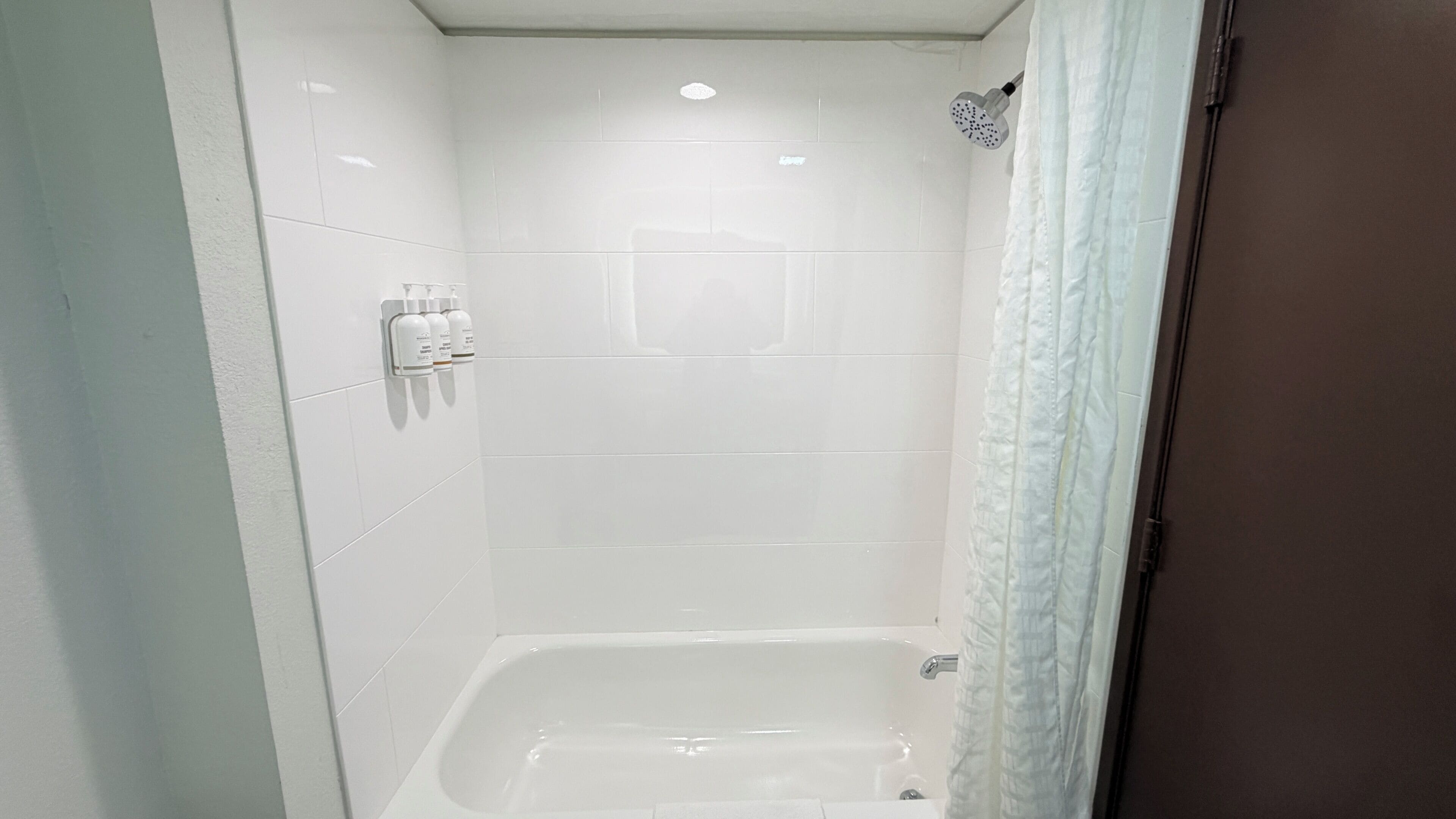 A bathroom with a bathtub, a showerhead, and a hand dryer.