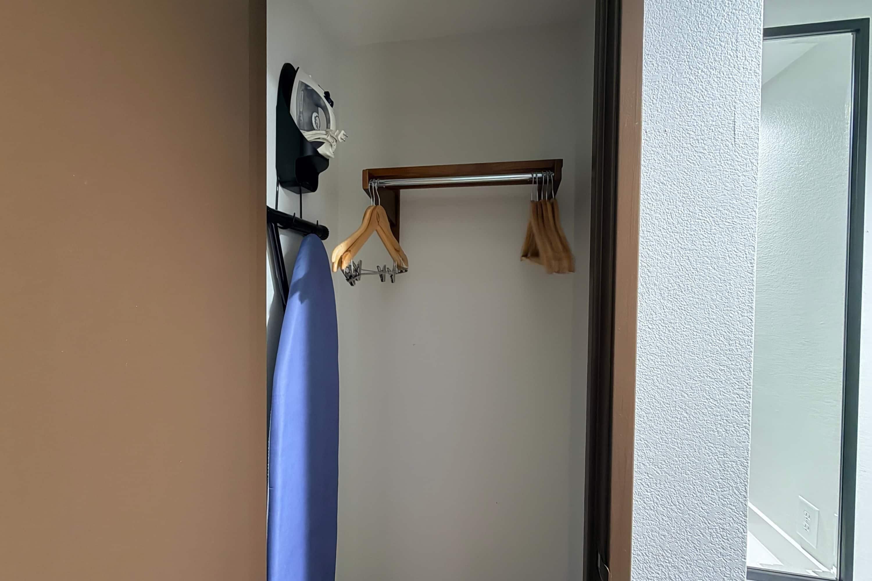 A room with a wooden hanger bar, a blue towel, and a white wall.