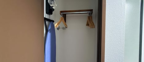 A room with a wooden hanger bar, a blue towel, and a white wall.