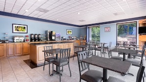 A restaurant with a counter, seating area, and large windows.