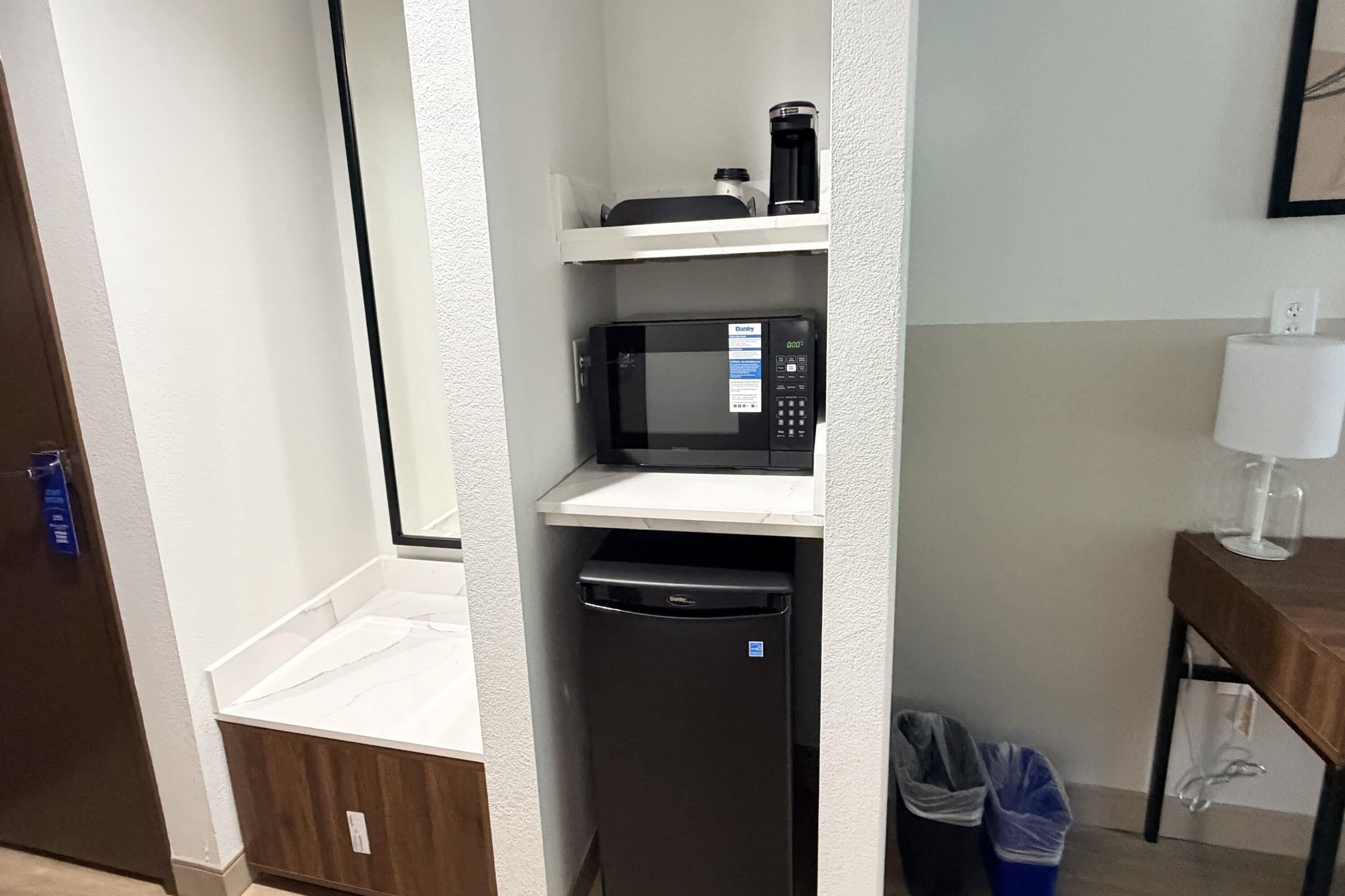 A compact kitchenette with a microwave, a coffee maker, and a dishwasher.