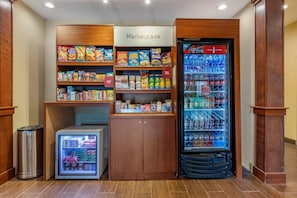 Eine Küchenzeile mit Kühlschrank, Gefriertruhe und Regalen, gefüllt mit Snacks und Getränken.