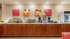 A breakfast bar with waffle makers, coffee machines, and a refrigerator.