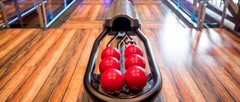 Une piste de bowling avec six quilles rouges disposées.