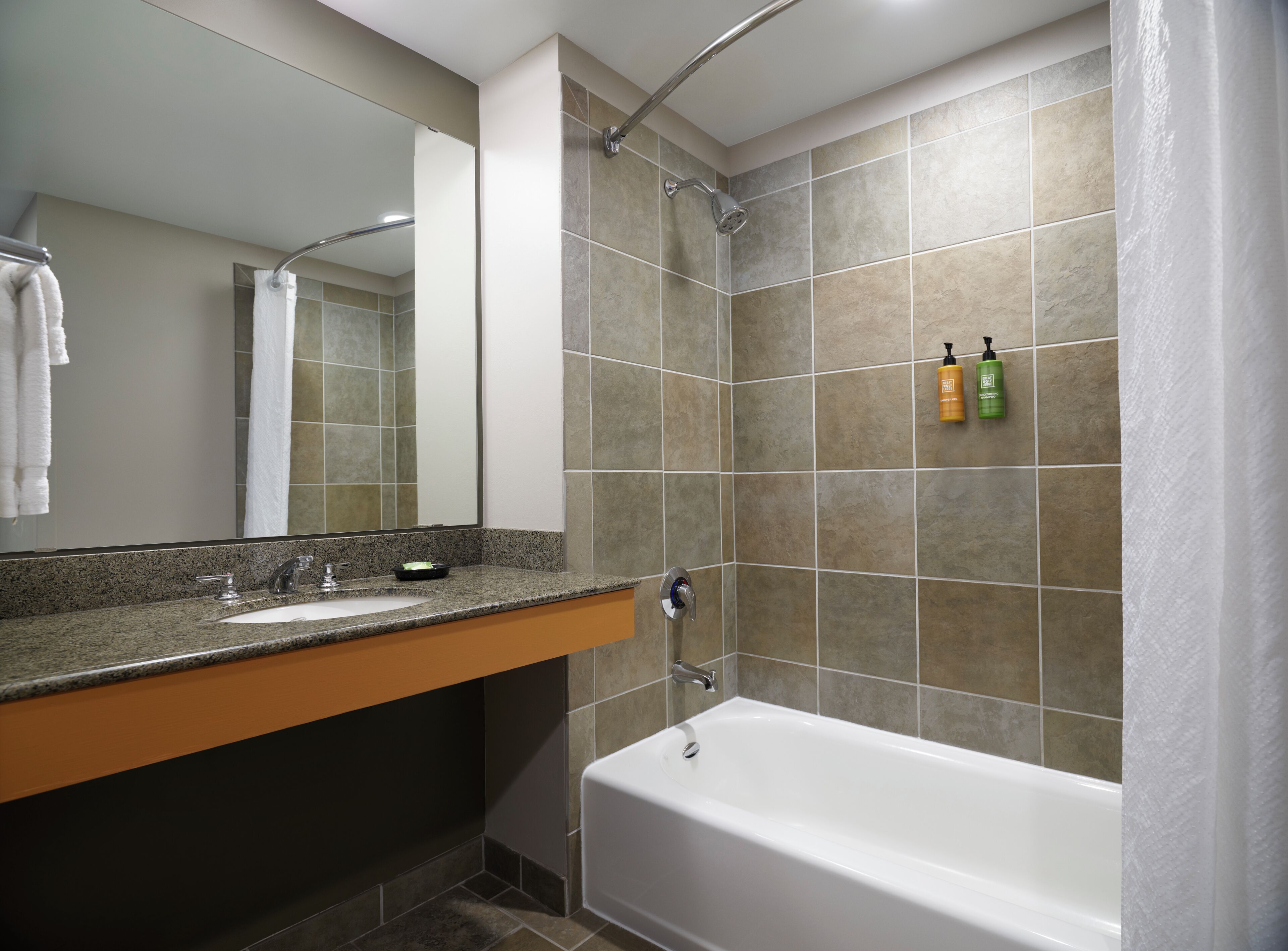 A bathroom with a bathtub, a sink, a mirror, and a shower.