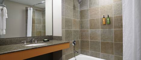 A bathroom with a bathtub, a sink, a mirror, and a shower.