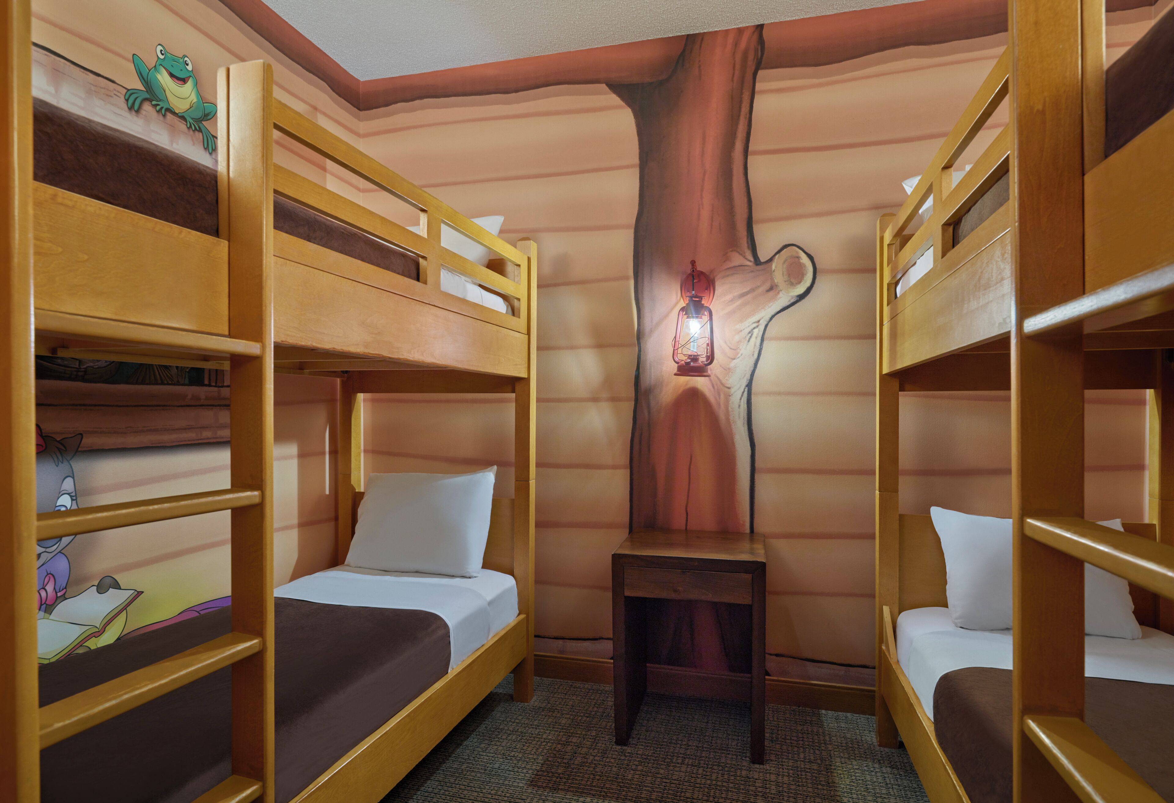 A room with bunk beds, a wooden tree trunk wall, a lantern, and a cartoon character on the wall.