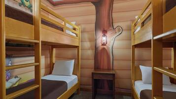 A room with bunk beds, a wooden tree trunk wall, a lantern, and a cartoon character on the wall.