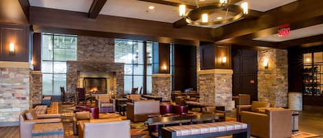 A spacious lobby with a fireplace, comfortable seating, and large windows.