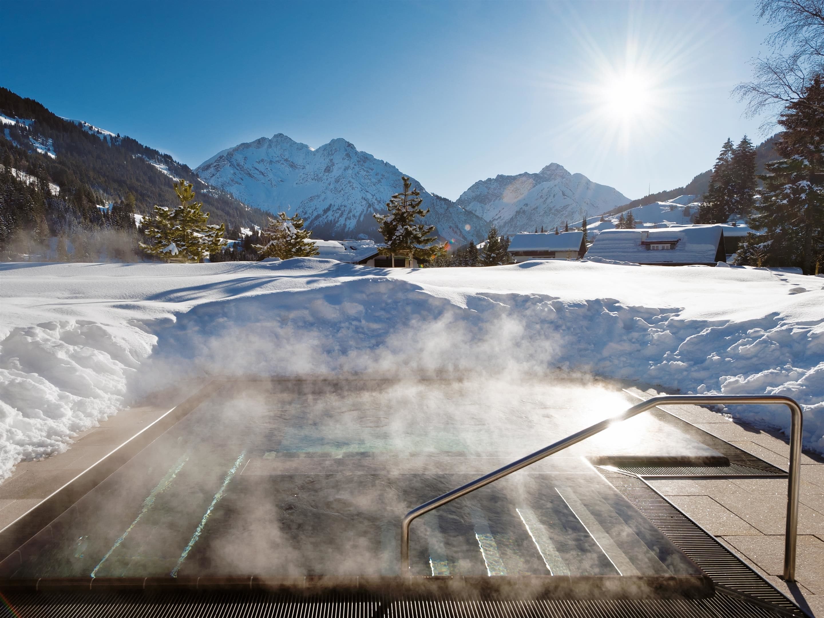 A snow-covered landscape with a steam room and mountains in the background.
