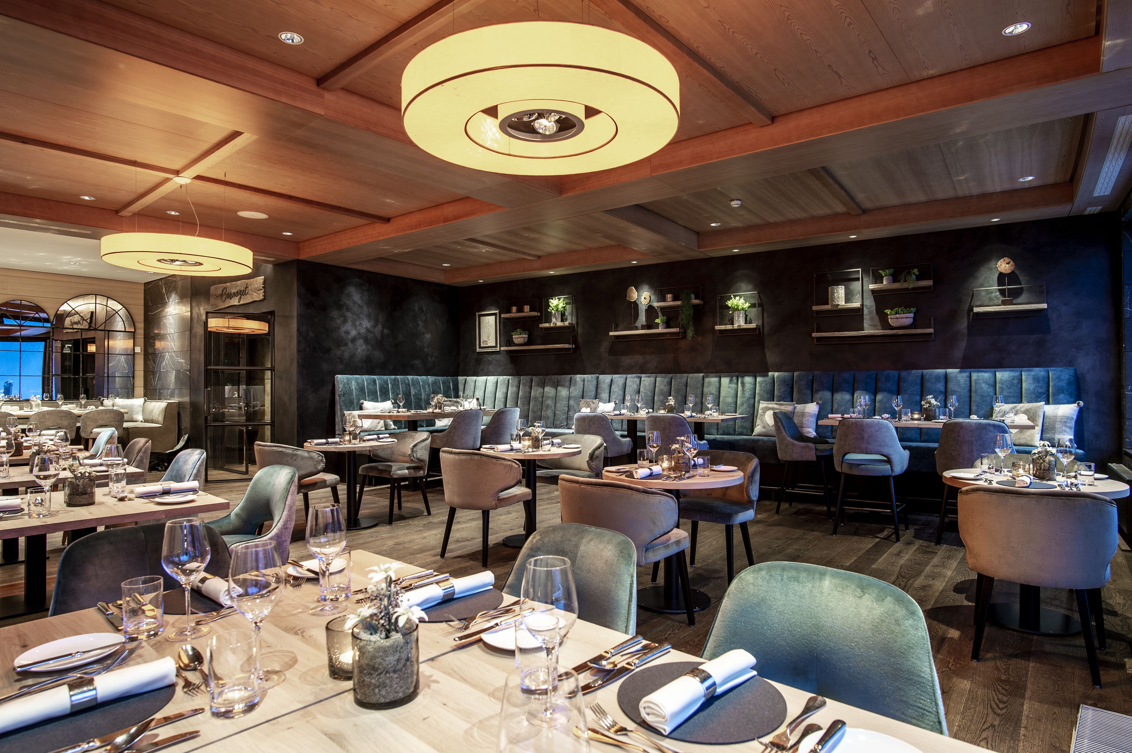 A restaurant with multiple dining tables, chairs, and a modern ceiling design.