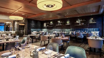 A restaurant with multiple dining tables, chairs, and a modern ceiling design.