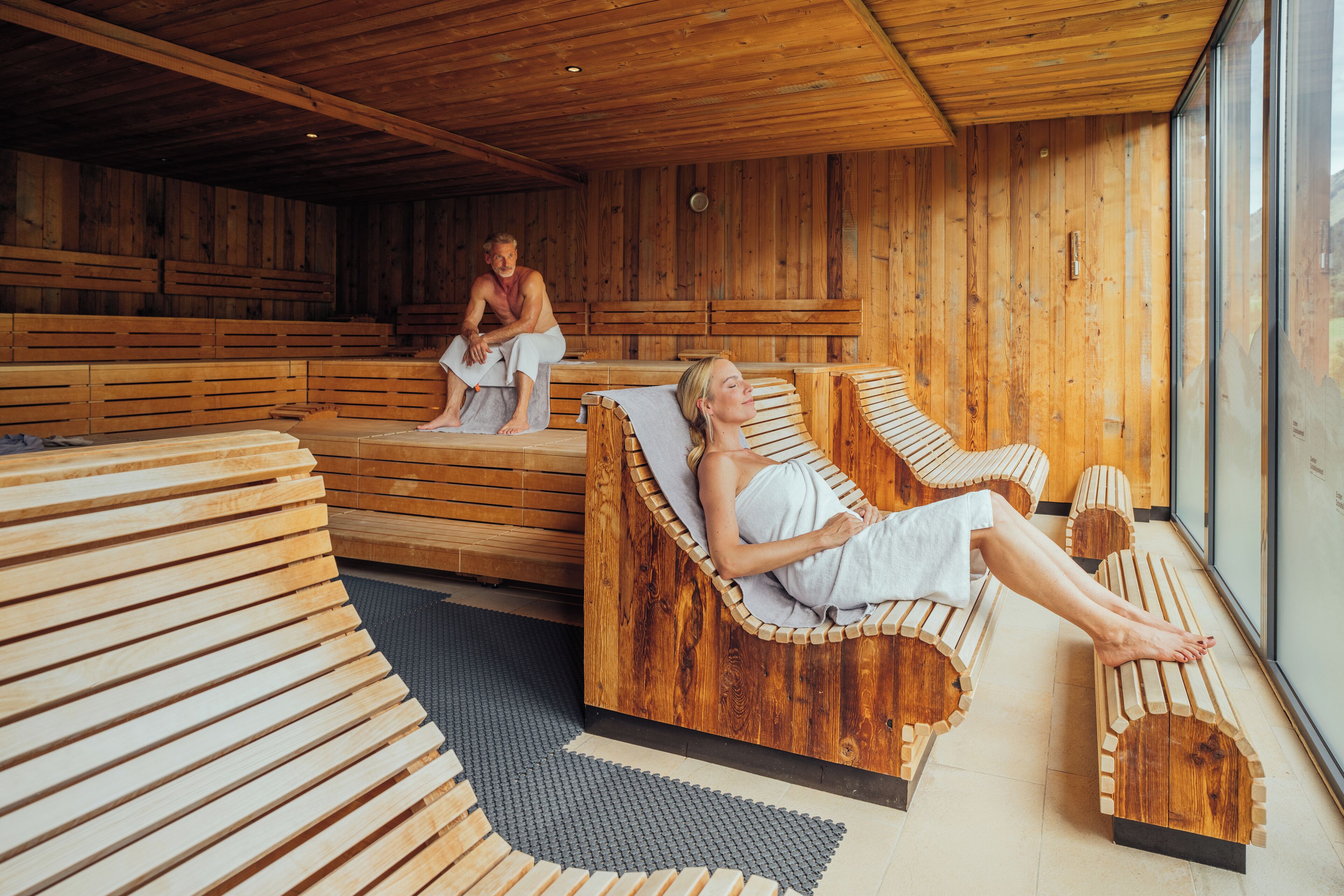 Un sauna en bois, doté de bancs et d’un mur en verre.