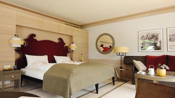 Une chambre d’hôtel avec un grand lit, des tables de chevet, un canapé, une table basse, un miroir et des tableaux encadrés au mur.