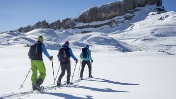 Un gruppo di persone scia sulle montagne innevate con scogliere rocciose sullo sfondo.