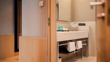 A modern bathroom with a wooden floor, a white sink with a mirror, and a towel rack.