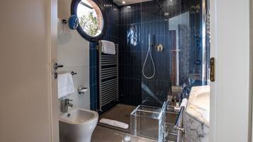 Een moderne badkamer met een bidet, een douchecabine van glas en een marmeren wastafel.