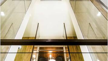 Un interno moderno con ringhiera in vetro, pavimento in legno e un'area salotto con tavolo e sedie.