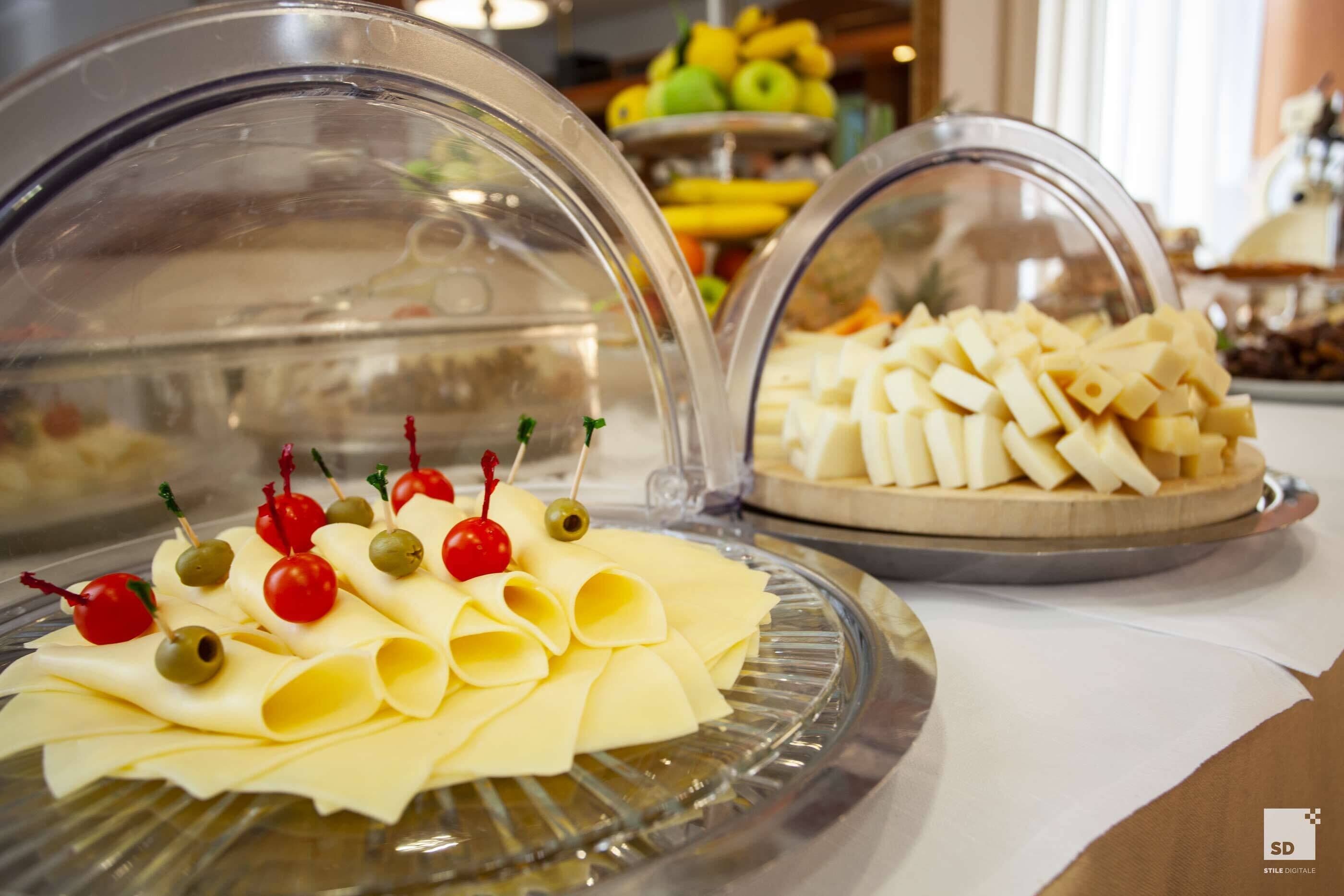 En buffet med overdækkede fade med ost og pasta.