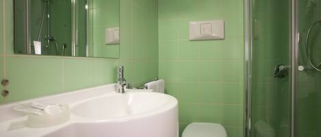 A bathroom with a white sink, a toilet, and a glass shower enclosure.