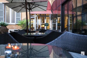 Un área de estar al aire libre con sillas de mimbre y una mesa, una recepción y un letrero que indica la zona de recepción.