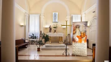 Interior de una iglesia con un altar de mármol, una estatua y una cruz.