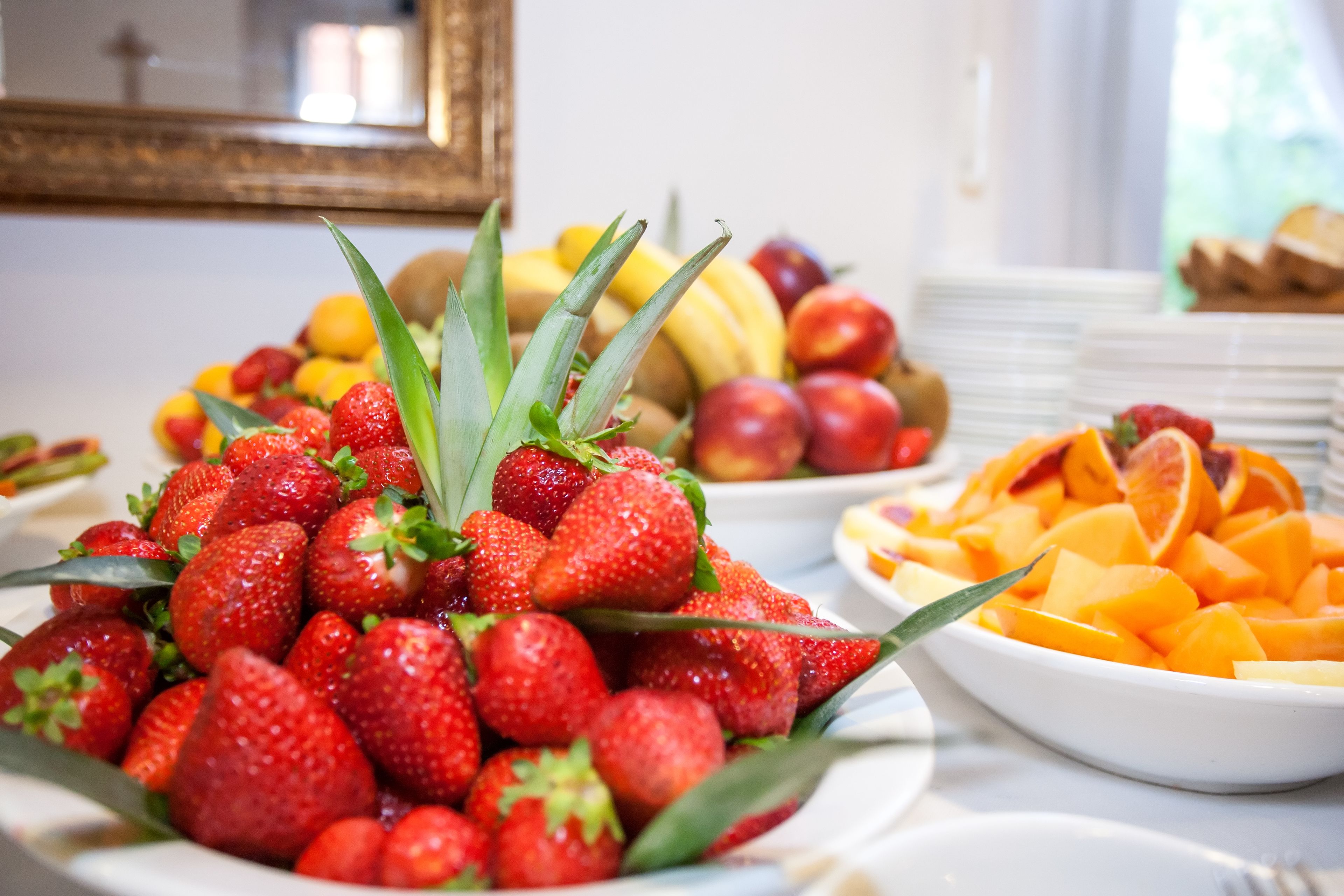 Una mesa de buffet con diversas frutas como fresas, melocotones y melón cantalupo.