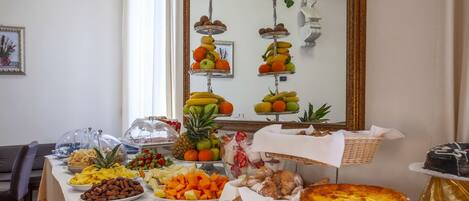 Una mesa de buffet con diversos alimentos y un espejo que refleja puestos de fruta.