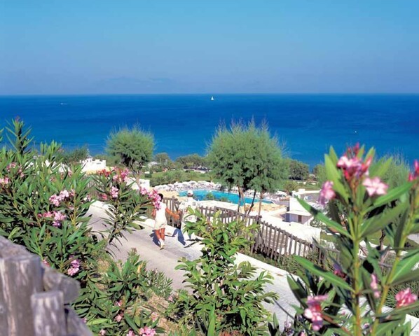 A resort with a pool, a view of the sea, and a person walking. - Lagas Aegean Village (Kos)