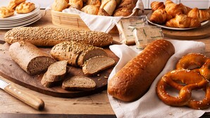 Diverses classes de pa i pastissos sobre una taula de fusta en un ambient de cuina.