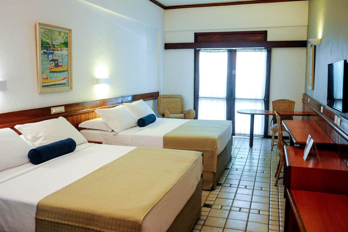 A hotel room with two beds, a dining table, chairs, and a television.