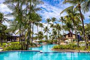 A pool surrounded by palm trees and lounge chairs, with a building in the background. - Summerville All Inclusive Resort  (Ipojuca)