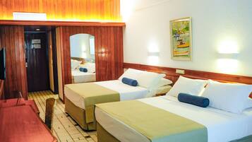 Habitación de hotel con dos camas, cabecera de madera, puerta de madera, televisor y un cuadro en la pared.