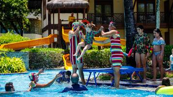 A swimming pool area with a slide, lounge chairs, and a poolside deck.