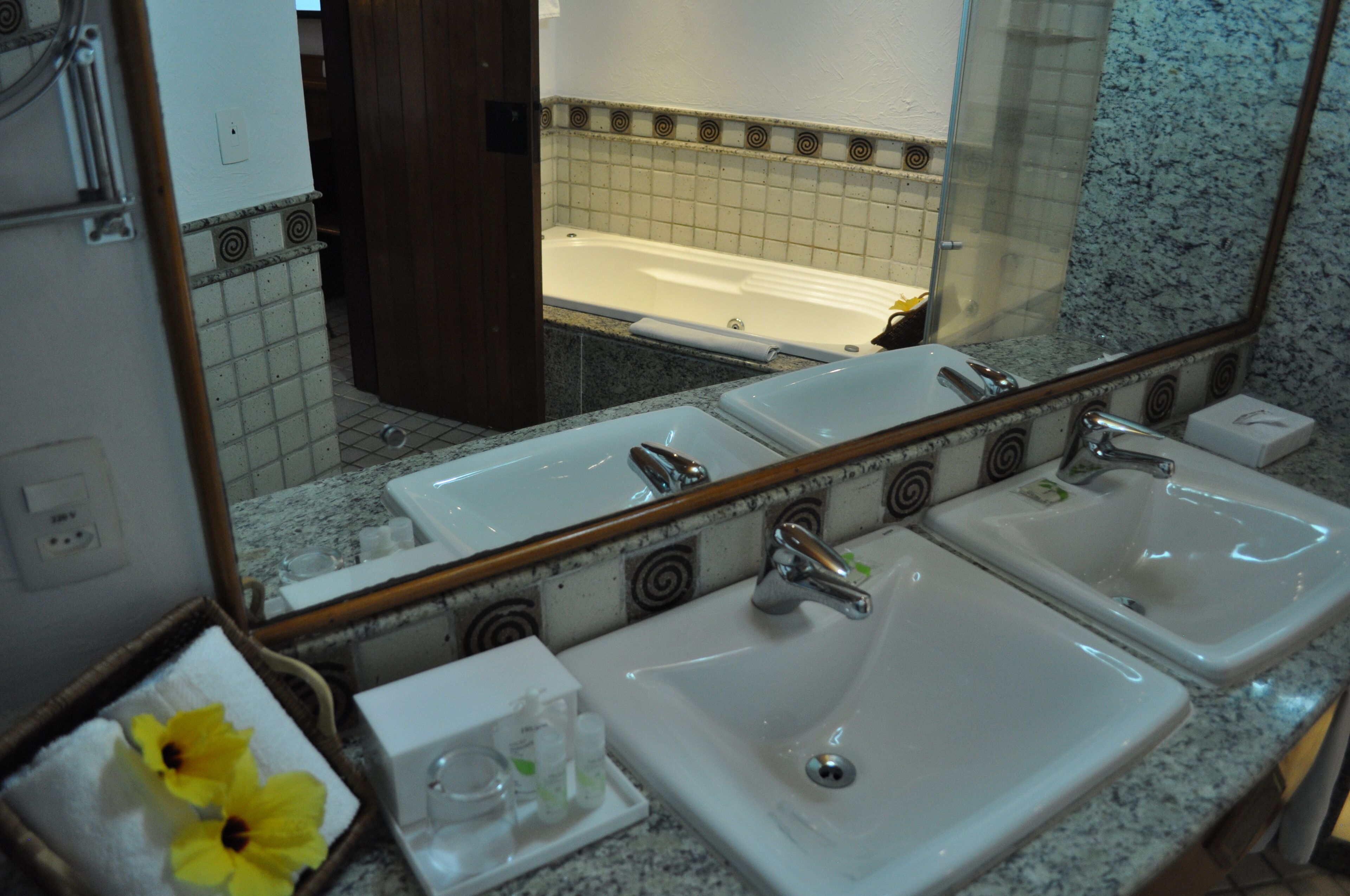 A bathroom with three sinks, a large mirror, and a bathtub.