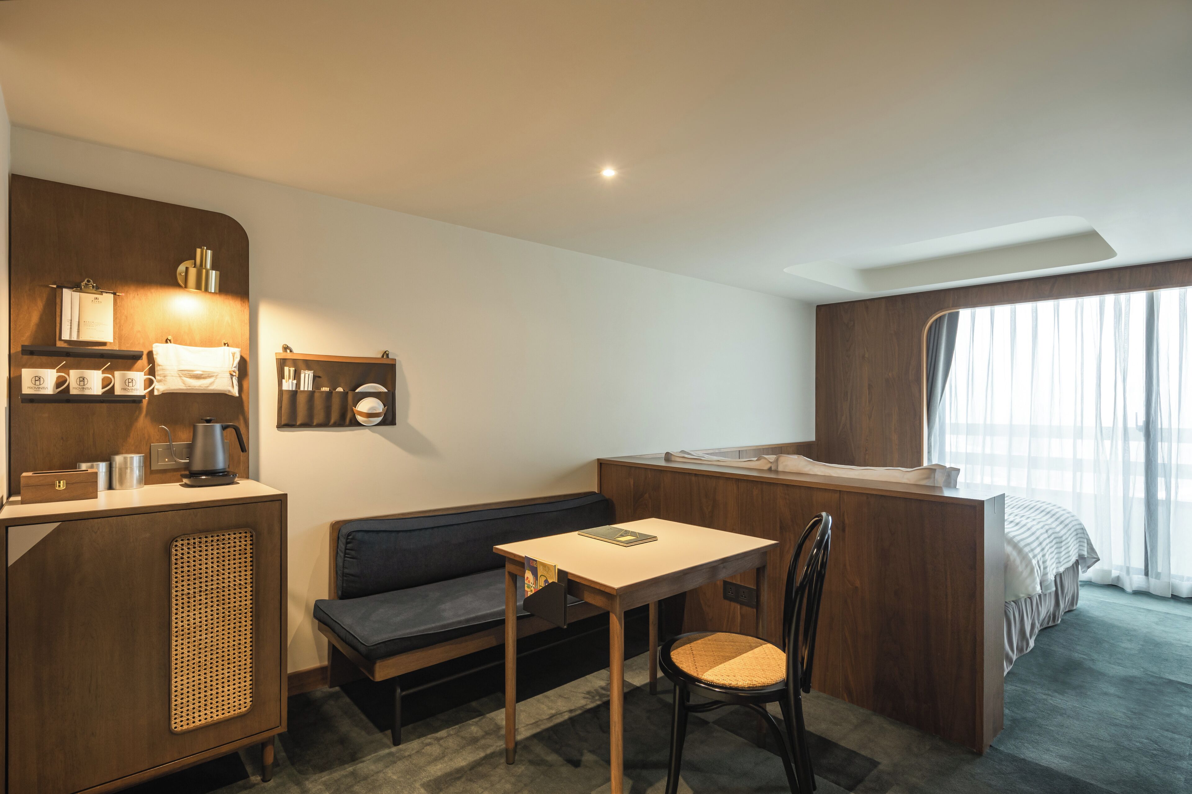 Une chambre d’hôtel compacte comprenant un coin cuisine, un canapé, une petite table et un lit simple.